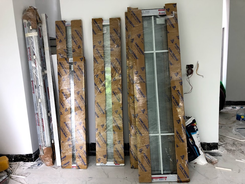 Cửa nhôm kính Austdoor mới đóng gói dựng sát tường trong nhà đang thi công